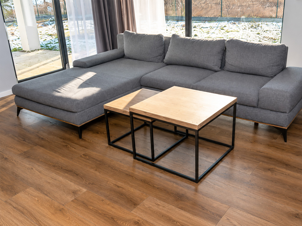 Living room with a gray sectional sofa on medium brown wood-look vinyl plank flooring